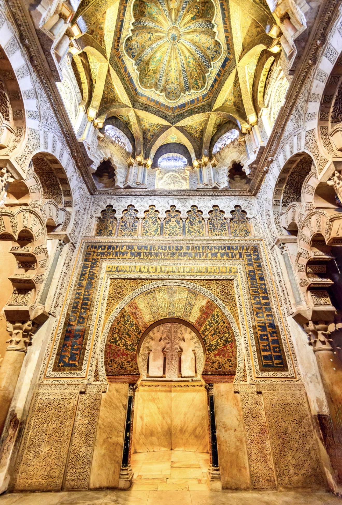 The richly decorated golden mihrab inside the Great Mosque of Córdoba, framed by intricate horseshoe arches and gilded mosaics